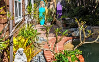 Brick Path with plumeria and St. Francis statue at the 2022 Gate and Garden Tour